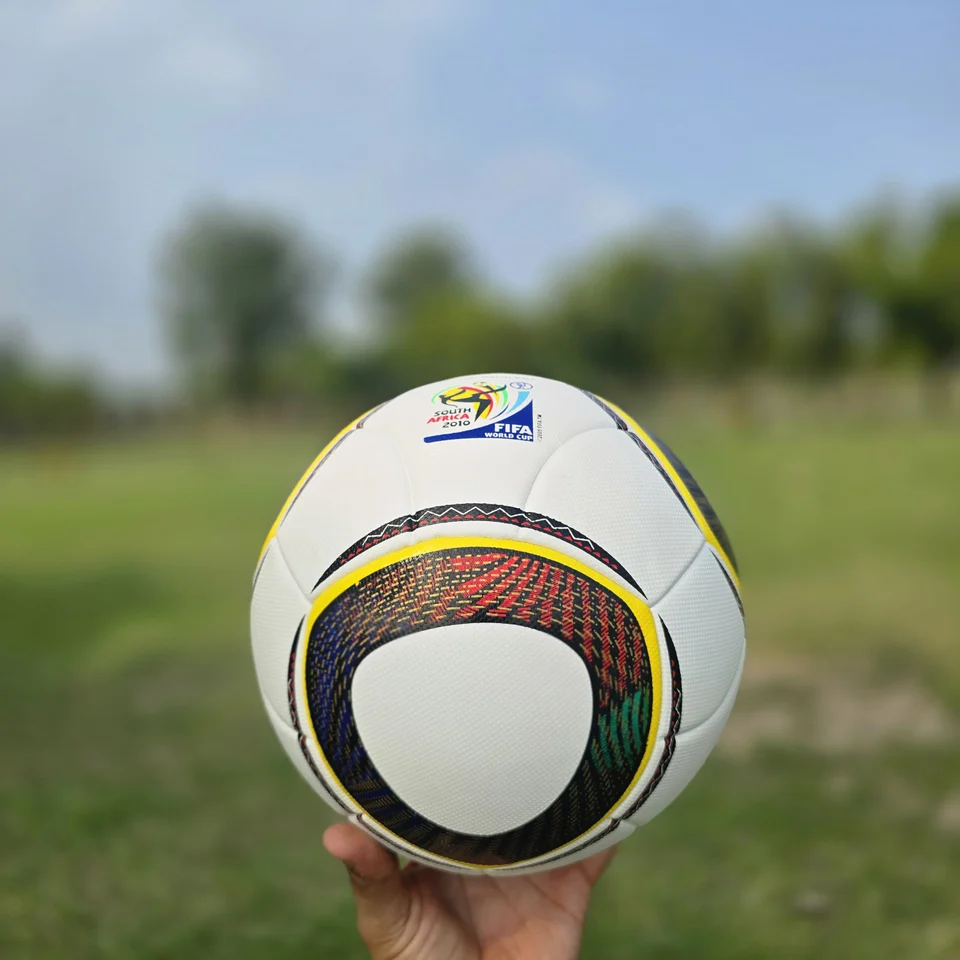 Black Gold Circular Panel Thermal Bonded Football front view - white thermal bonded football with black, gold, green, and red circular panel artwork