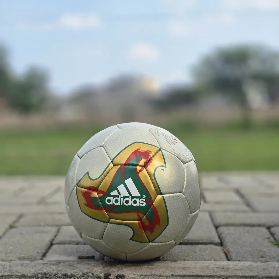 Cream Geometric Panel Hand-Stitched Football front view - cream handmade football with tan, orange, and green geometric panel artwork