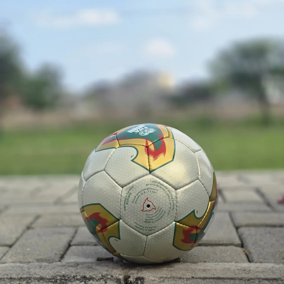 Cream Geometric Panel Hand-Stitched Football side view - cream handmade football with tan, orange, and green geometric panel artwork