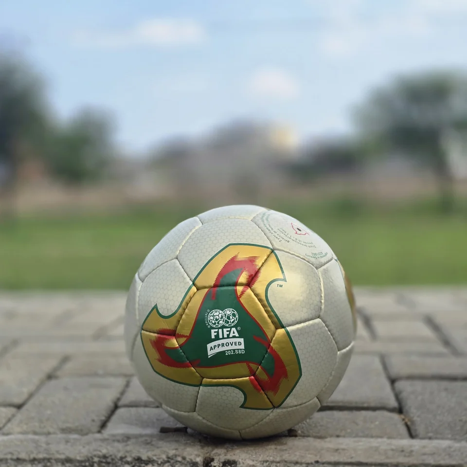 Cream Geometric Panel Hand-Stitched Football side view - cream handmade football with tan, orange, and green geometric panel artwork