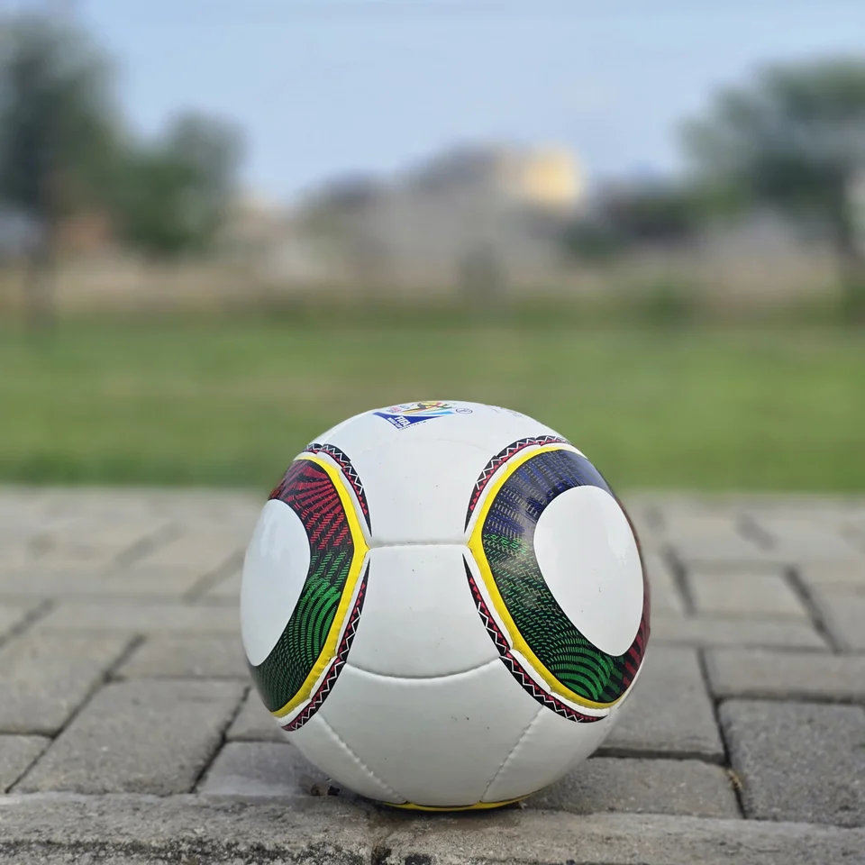 Green Yellow Accent Hand-Stitched Football alternate front angle - white handmade football with green, yellow, black, and red curved accent panels