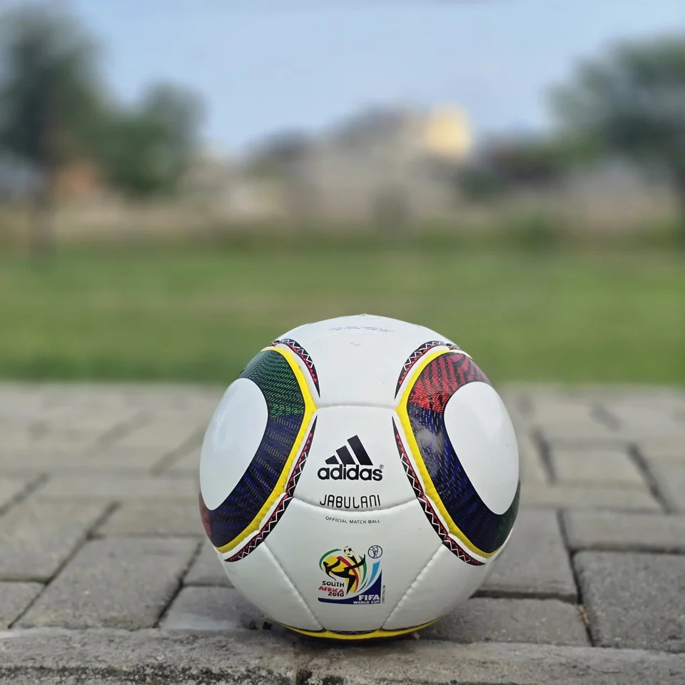 Green Yellow Accent Hand-Stitched Football front view - white handmade football with green, yellow, black, and red curved accent panels