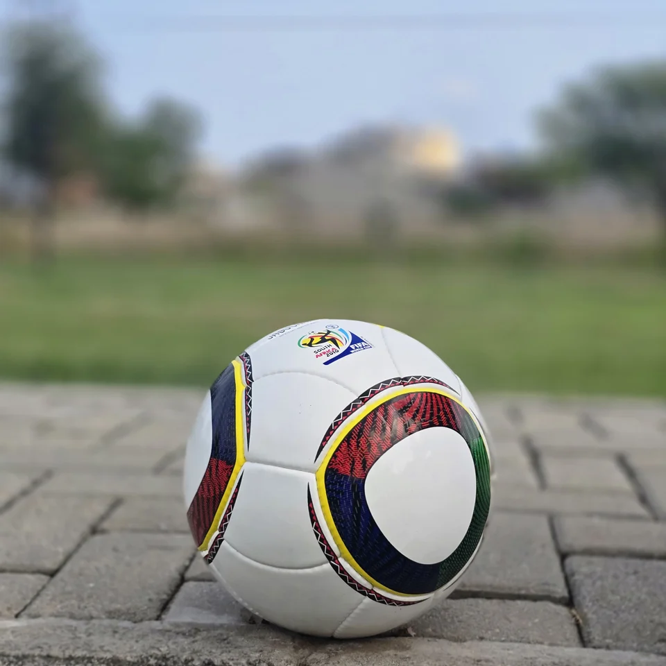 Green Yellow Accent Hand-Stitched Football side view - white handmade football with green, yellow, black, and red curved accent panels