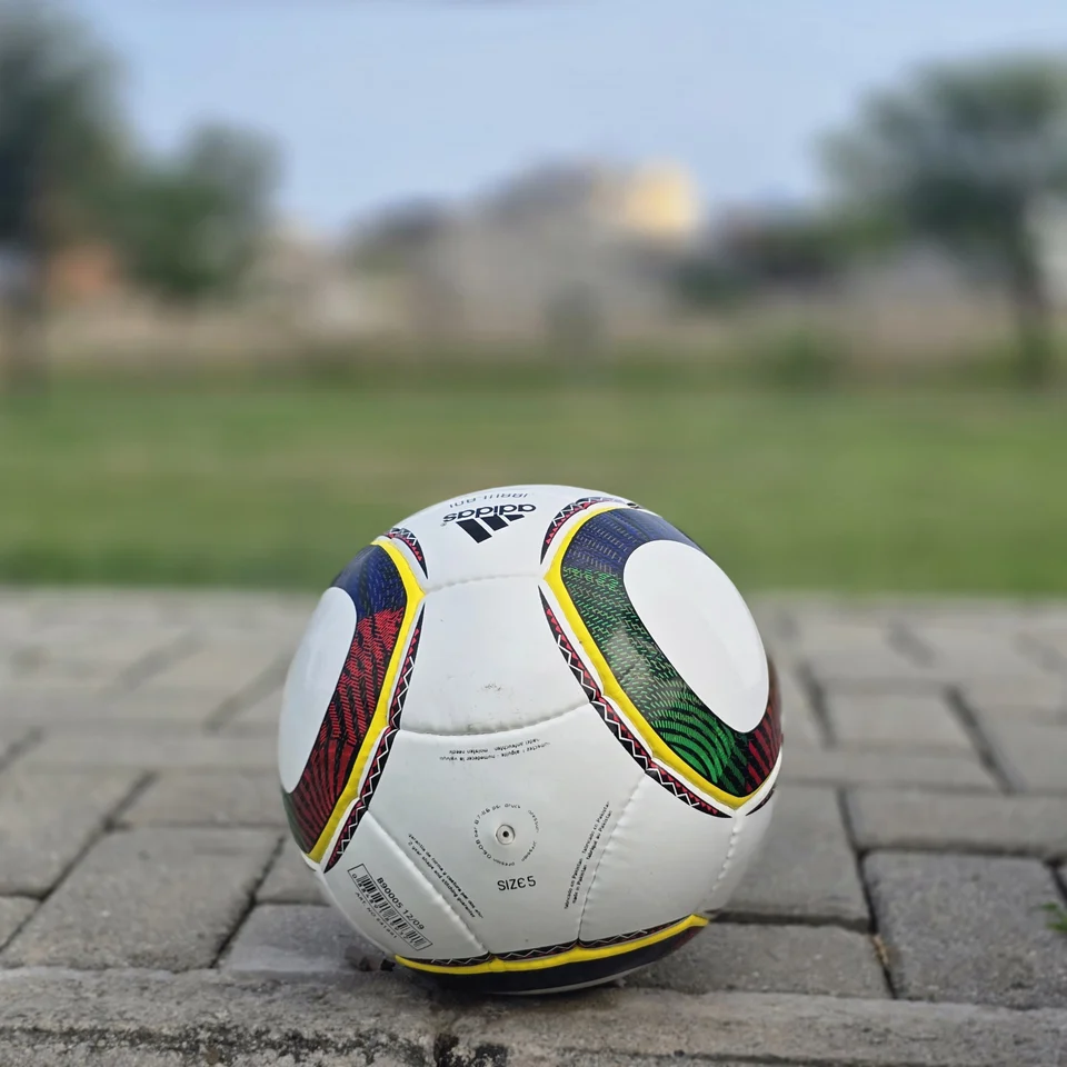 Green Yellow Accent Hand-Stitched Football side view - white handmade football with green, yellow, black, and red curved accent panels
