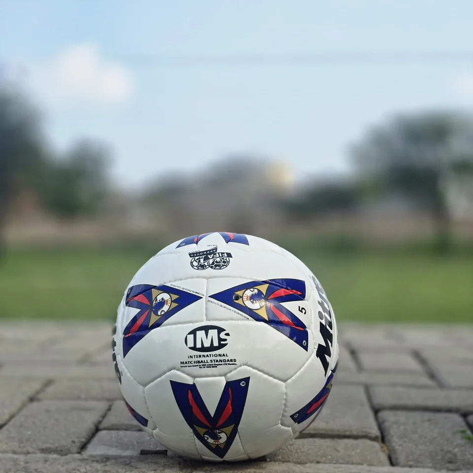 Red & Blue Arrow Panel Hand-Stitched Football construction detail - white handmade football with red and blue arrow-style panel graphics