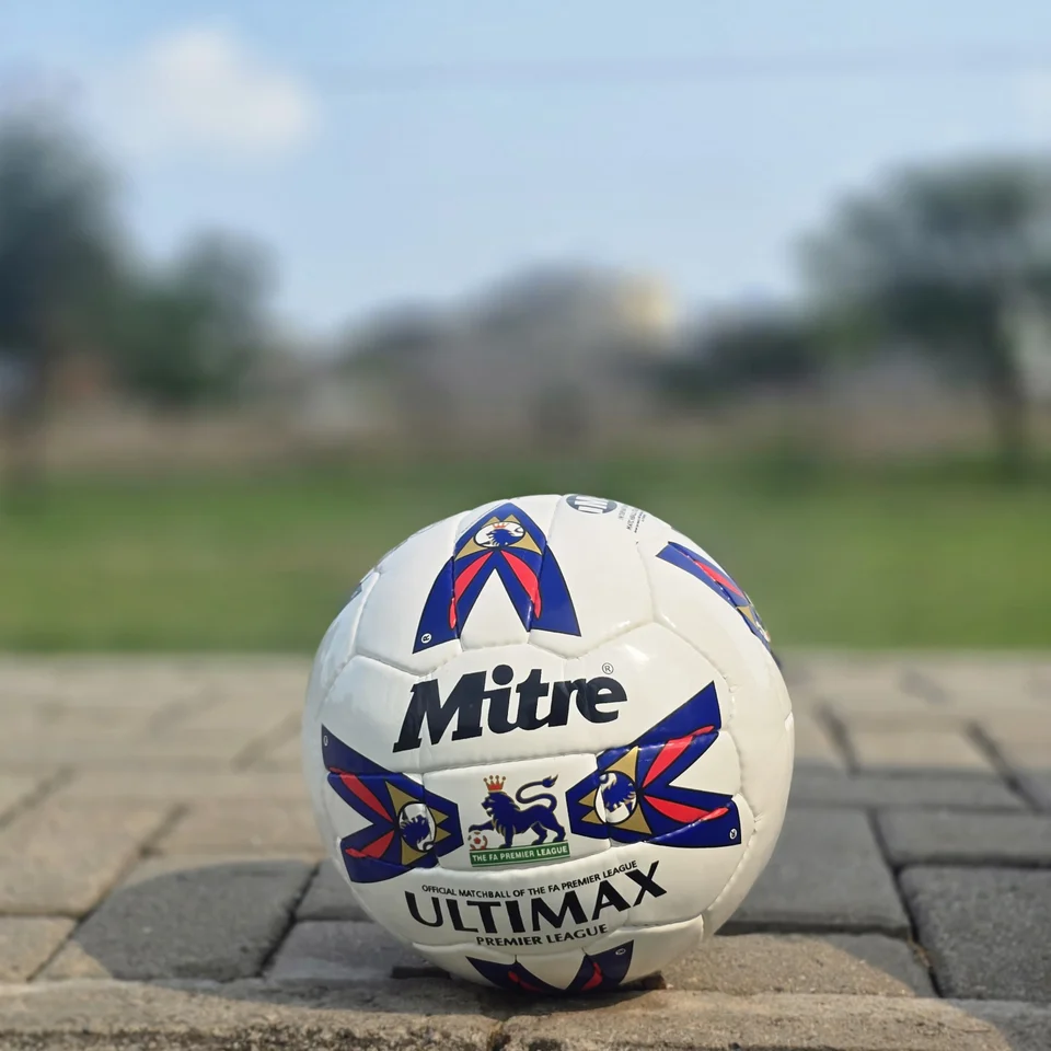 Red & Blue Arrow Panel Hand-Stitched Football supporting view - white handmade football with red and blue arrow-style panel graphics