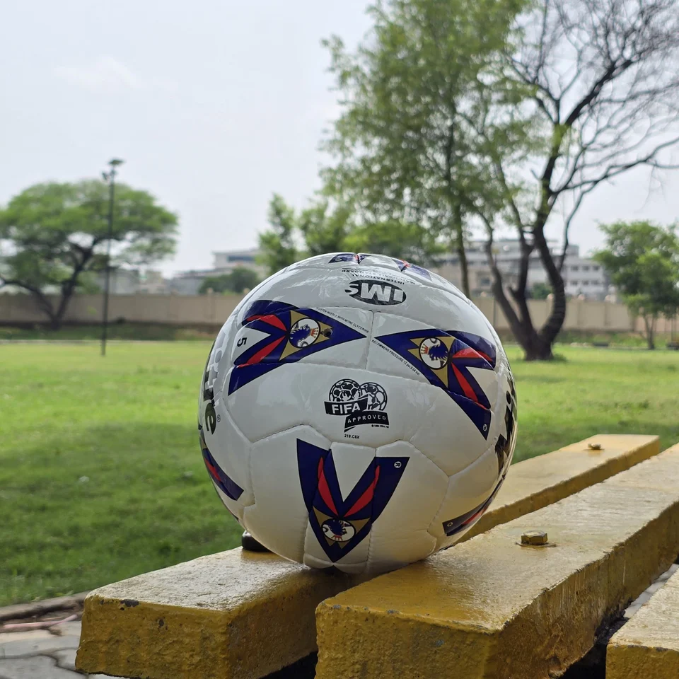 Red Blue Arrow Match-Style Hand-Stitched Football front view - white handmade football with red and blue arrow panel artwork photographed on a wooden bench