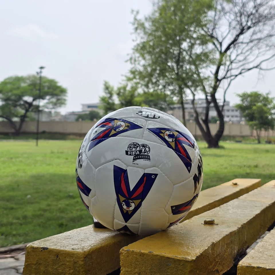 Red Blue Arrow Match-Style Hand-Stitched Football side view - white handmade football with red and blue arrow panel artwork photographed on a wooden bench