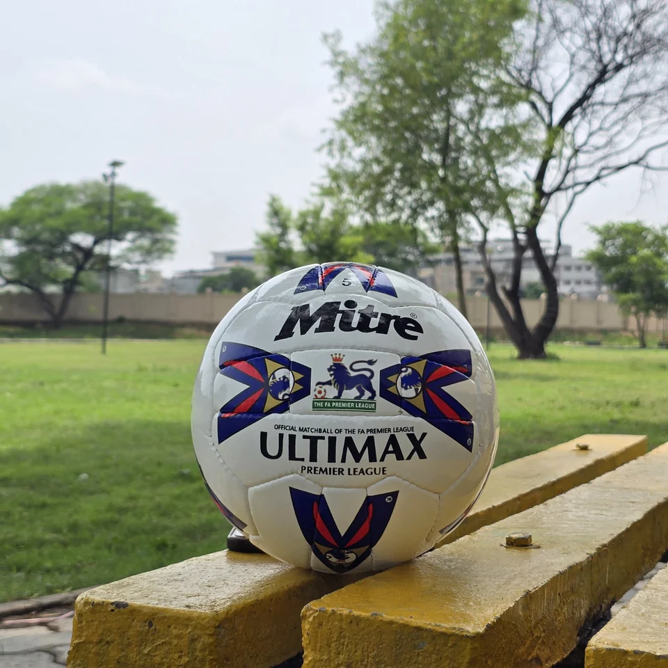 Red Blue Arrow Match-Style Hand-Stitched Football side view - white handmade football with red and blue arrow panel artwork photographed on a wooden bench