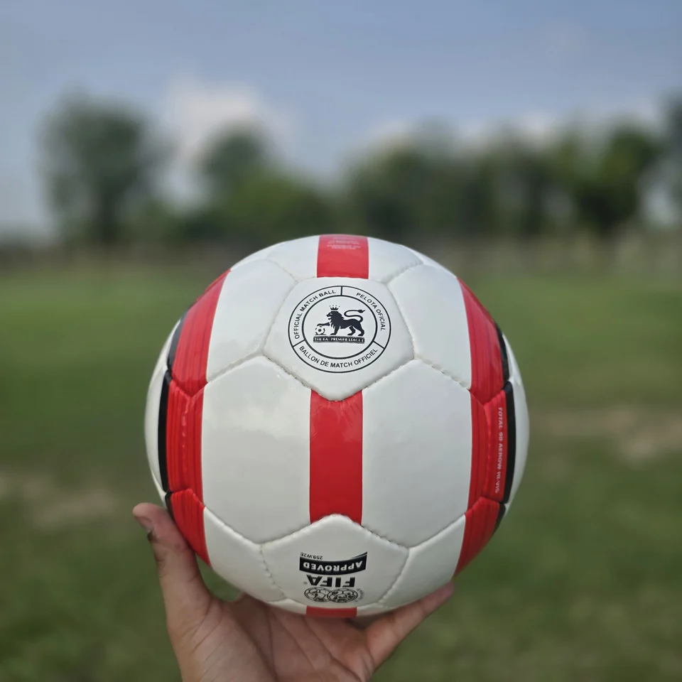 Red Stripe Badge Hand-Stitched Football side view - white handmade football with red vertical stripe panels and small badge-style artwork