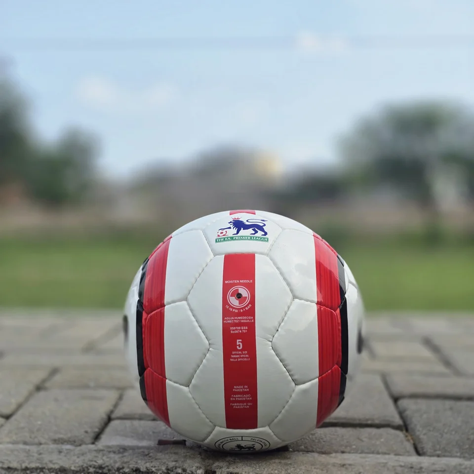 Red Stripe Custom Logo Hand-Stitched Football alternate front angle - white handmade football with red vertical stripes and a small lion-style graphic badge