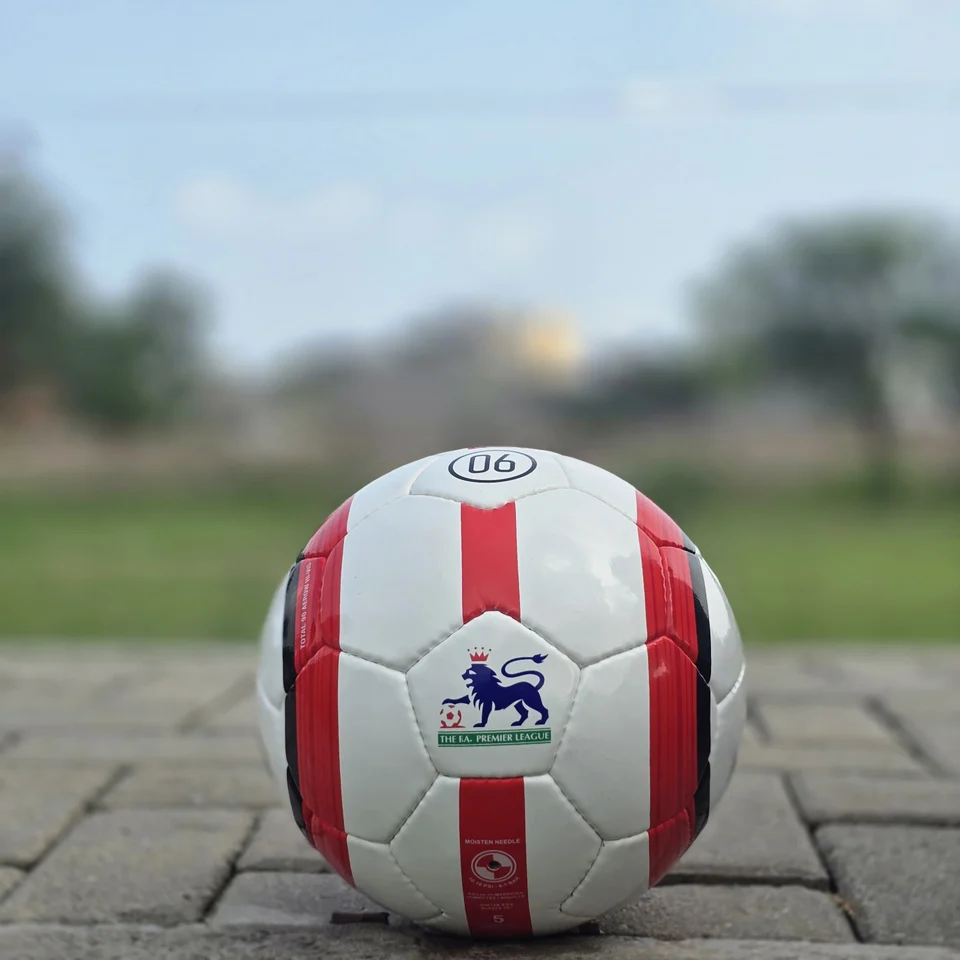 Red Stripe Custom Logo Hand-Stitched Football front view - white handmade football with red vertical stripes and a small lion-style graphic badge