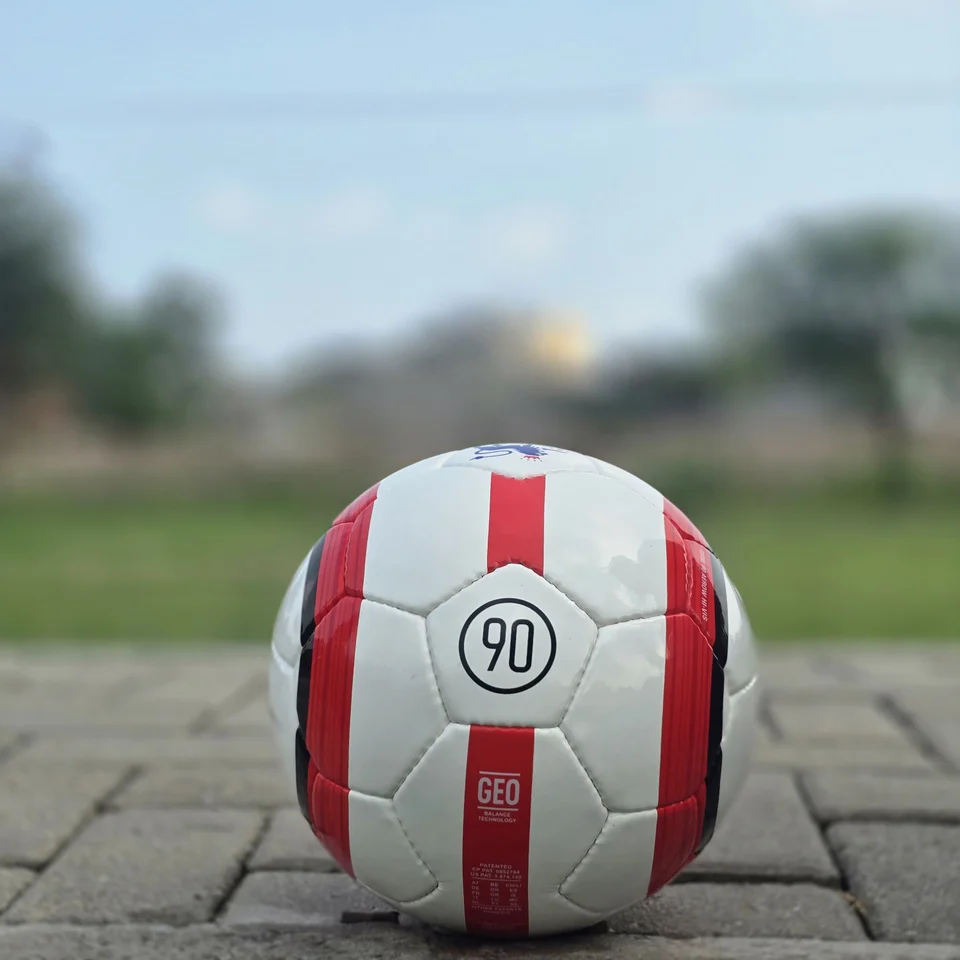 Red Stripe Custom Logo Hand-Stitched Football side view - white handmade football with red vertical stripes and a small lion-style graphic badge