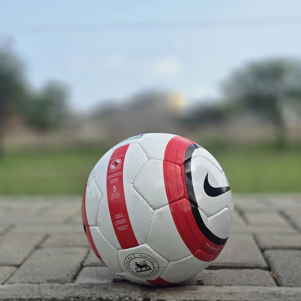 Red Stripe Custom Logo Hand-Stitched Football side view - white handmade football with red vertical stripes and a small lion-style graphic badge