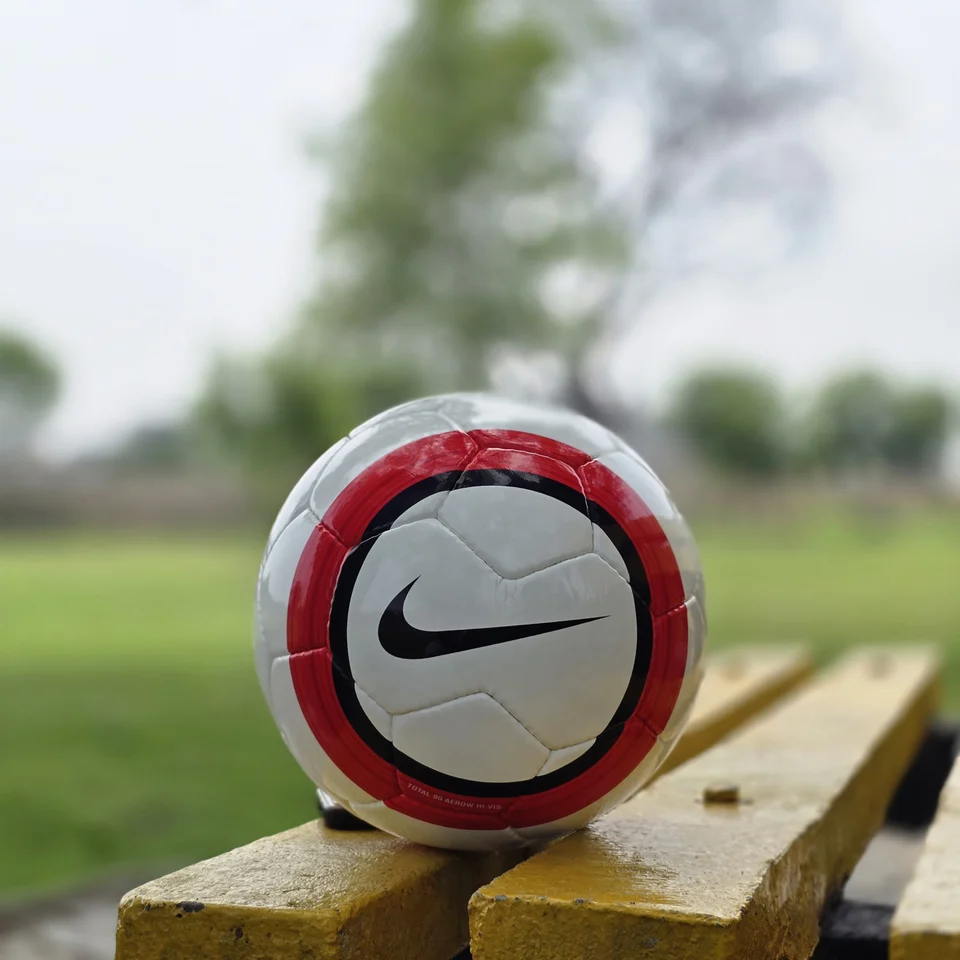 Red Stripe Lion Graphic Hand-Stitched Football design detail - white handmade football with red vertical stripes and a small lion-style printed graphic