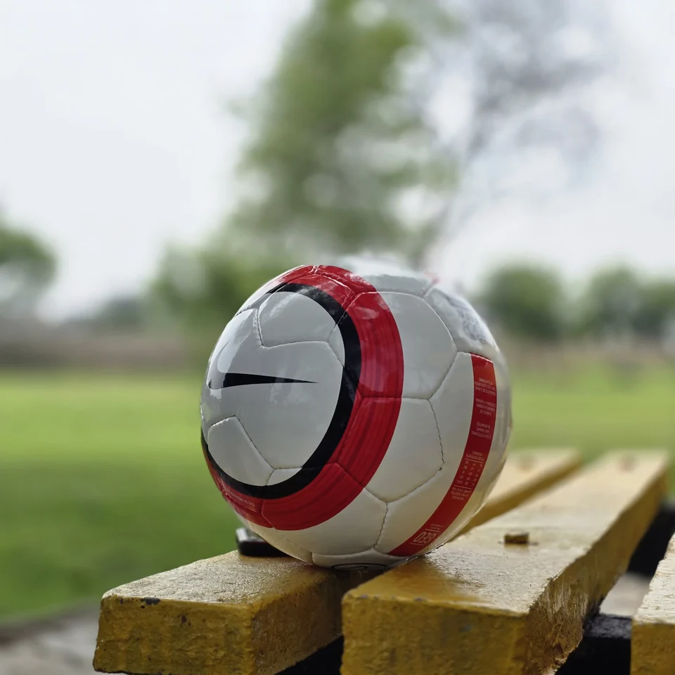 Red Stripe Lion Graphic Hand-Stitched Football side view - white handmade football with red vertical stripes and a small lion-style printed graphic