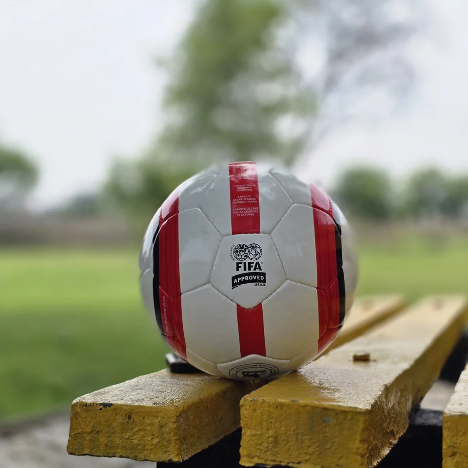 Red Stripe Lion Graphic Hand-Stitched Football side view - white handmade football with red vertical stripes and a small lion-style printed graphic