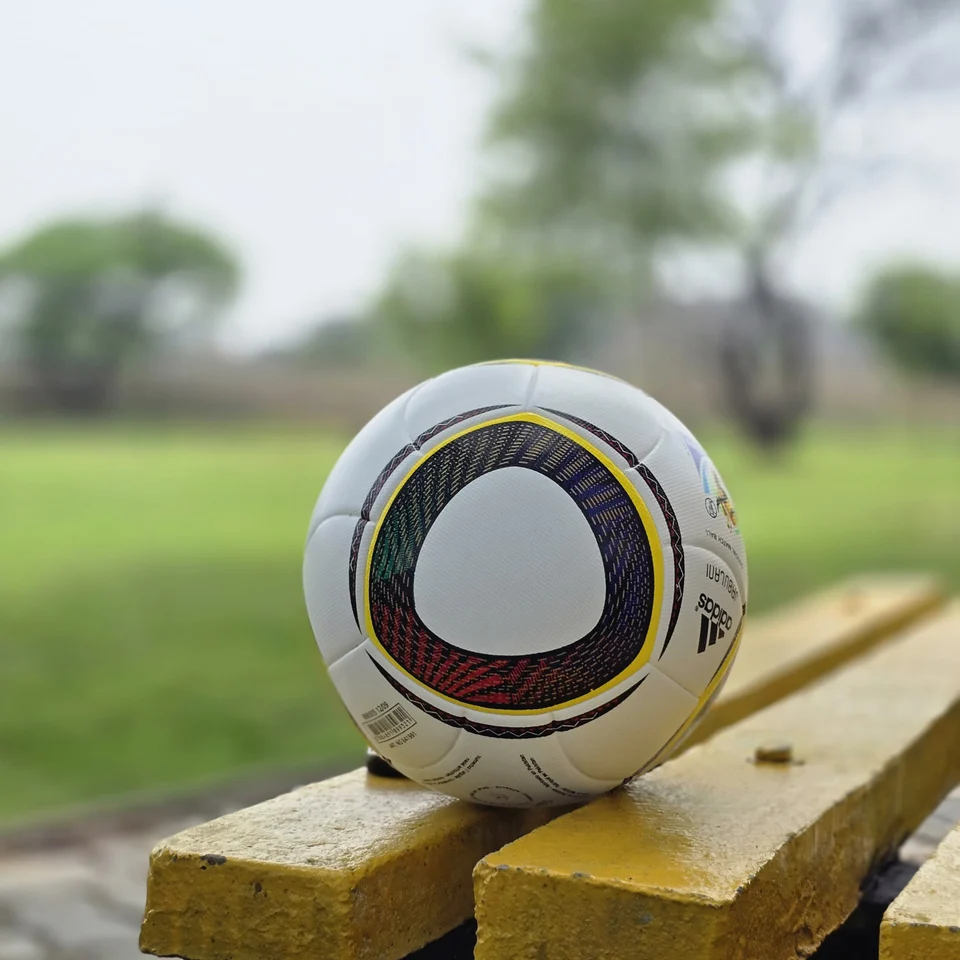 White Black Yellow Accent Hand-Stitched Football construction detail - white handmade football with black, yellow, green, and red accent panel graphics