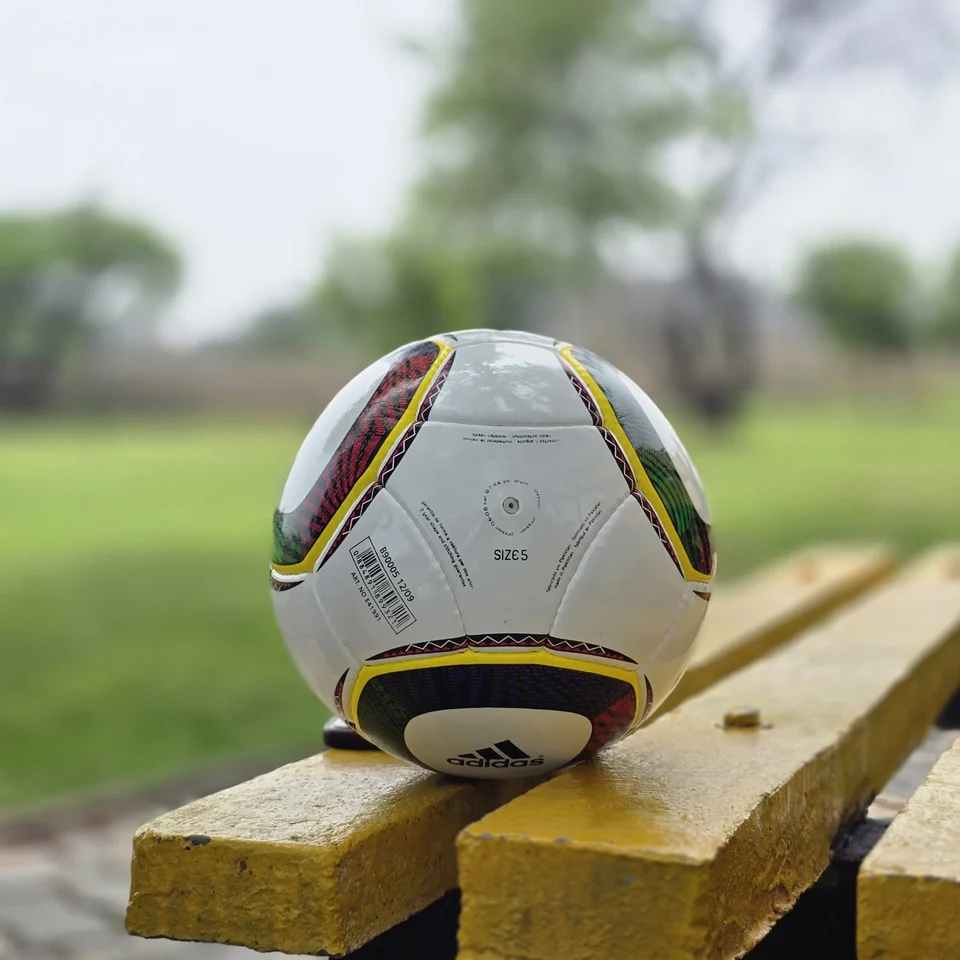 White Black Yellow Accent Hand-Stitched Football design detail - white handmade football with black, yellow, green, and red accent panel graphics