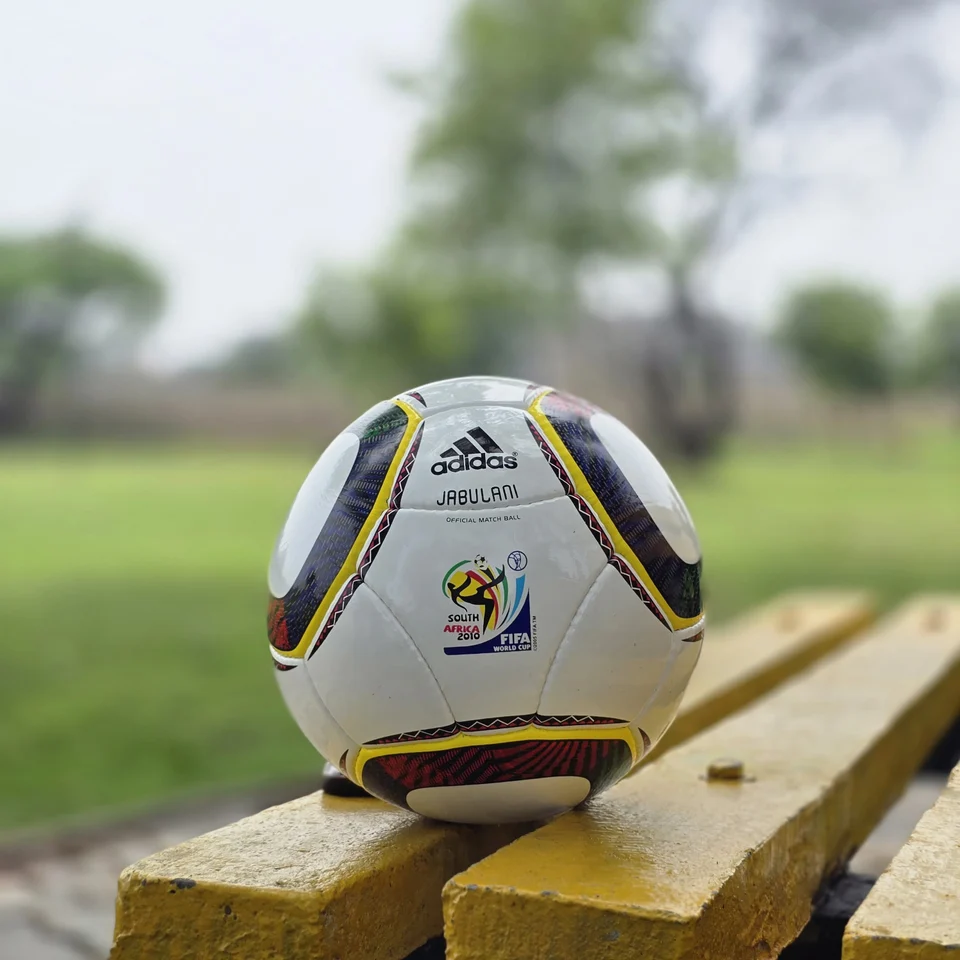 White Black Yellow Accent Hand-Stitched Football front view - white handmade football with black, yellow, green, and red accent panel graphics