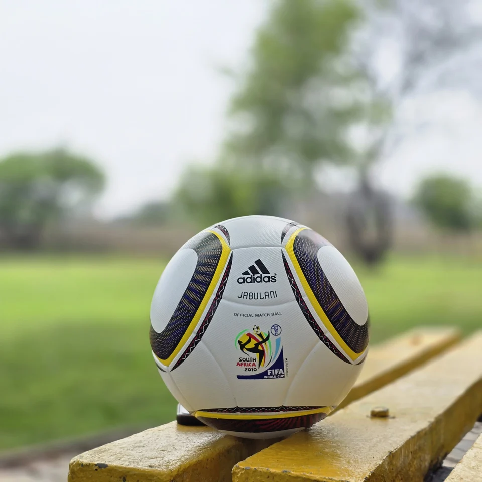 White Black Yellow Accent Hand-Stitched Football side view - white handmade football with black, yellow, green, and red accent panel graphics