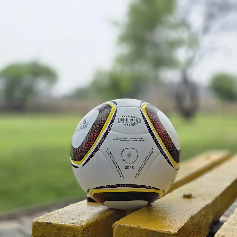 White Black Yellow Accent Hand-Stitched Football side view - white handmade football with black, yellow, green, and red accent panel graphics