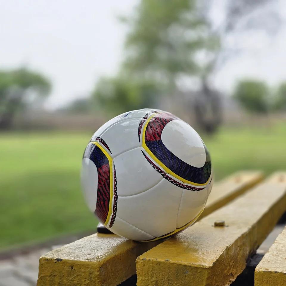 White Black Yellow Accent Hand-Stitched Football supporting view - white handmade football with black, yellow, green, and red accent panel graphics