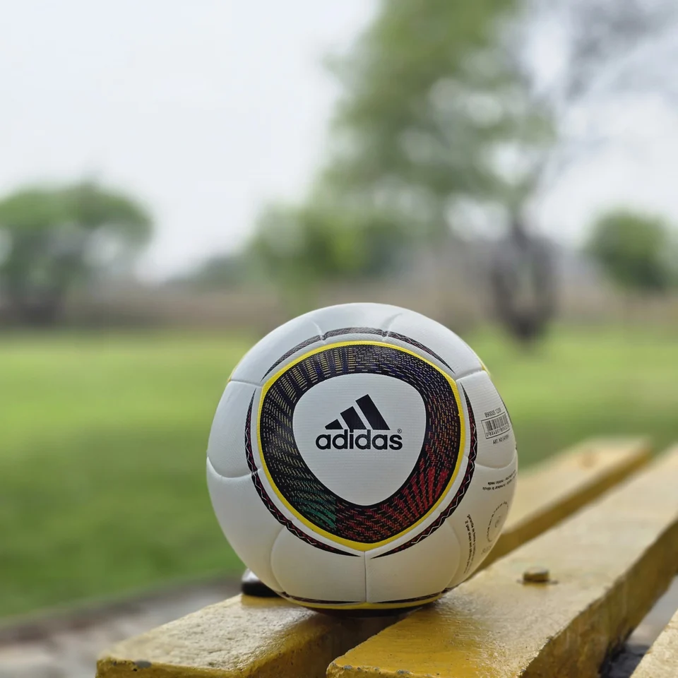 White Black Yellow Accent Hand-Stitched Football supporting view 09 - white handmade football with black, yellow, green, and red accent panel graphics