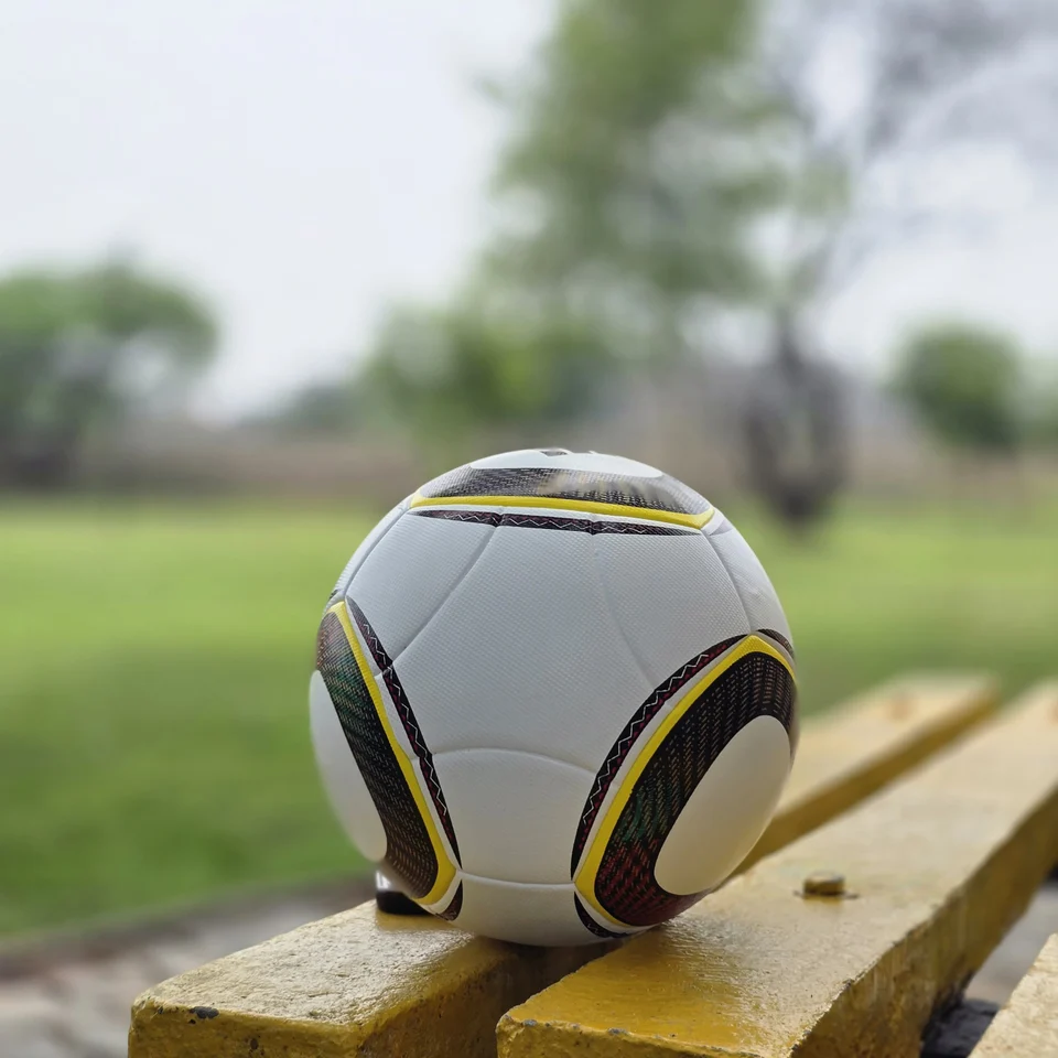 White Black Yellow Accent Hand-Stitched Football supporting view 11 - white handmade football with black, yellow, green, and red accent panel graphics