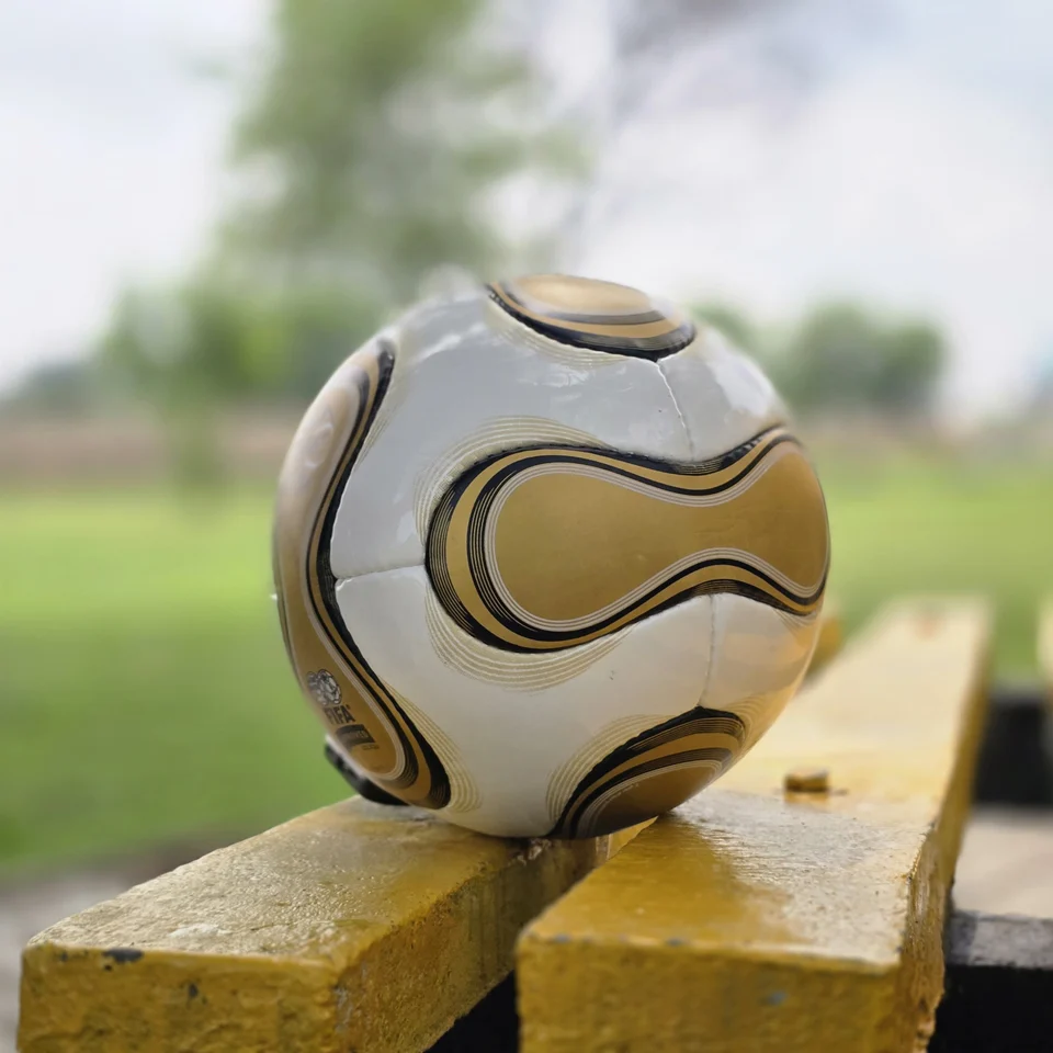 White Gold Wave Hand-Stitched Football supporting view - white handmade football with gold wave graphics and black trim