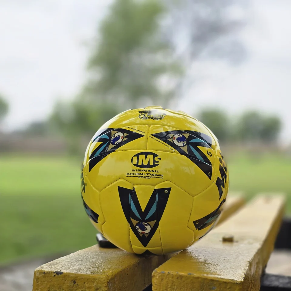 Yellow Black Crest Panel Hand-Stitched Football front view - yellow handmade football with black graphic panels and a small crest-style mark