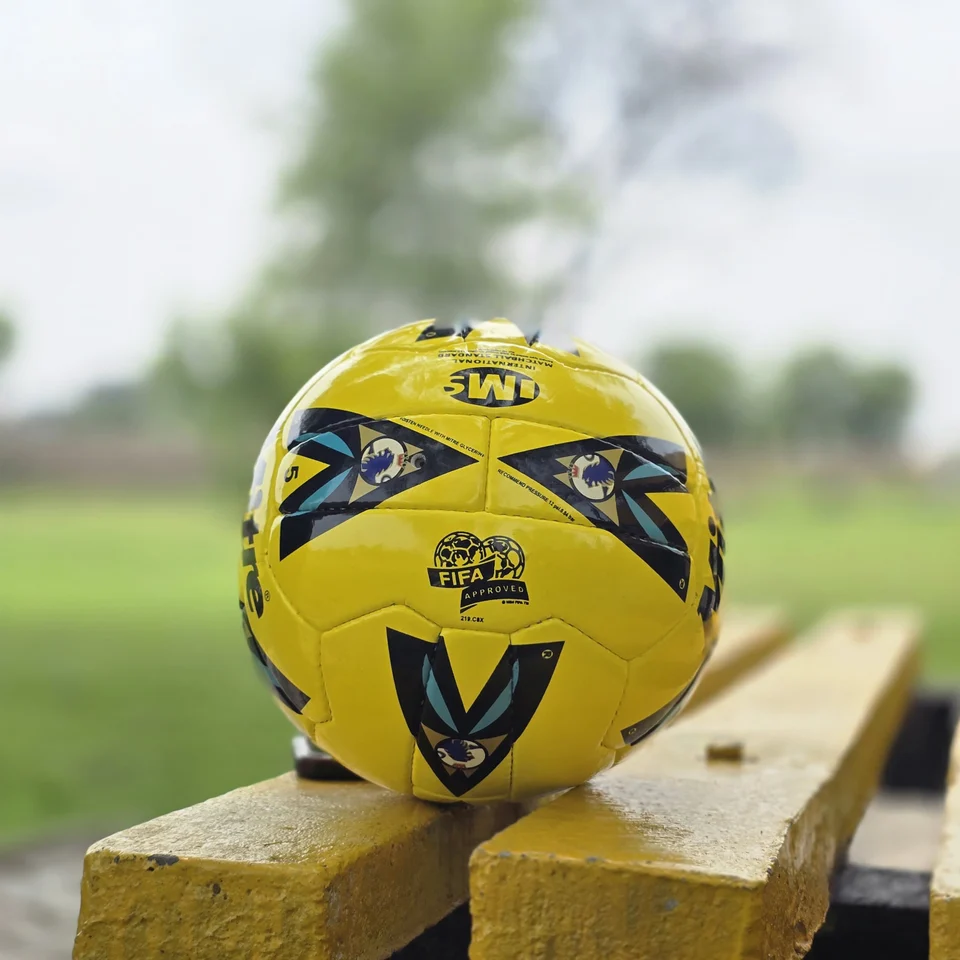 Yellow Black Crest Panel Hand-Stitched Football side view - yellow handmade football with black graphic panels and a small crest-style mark