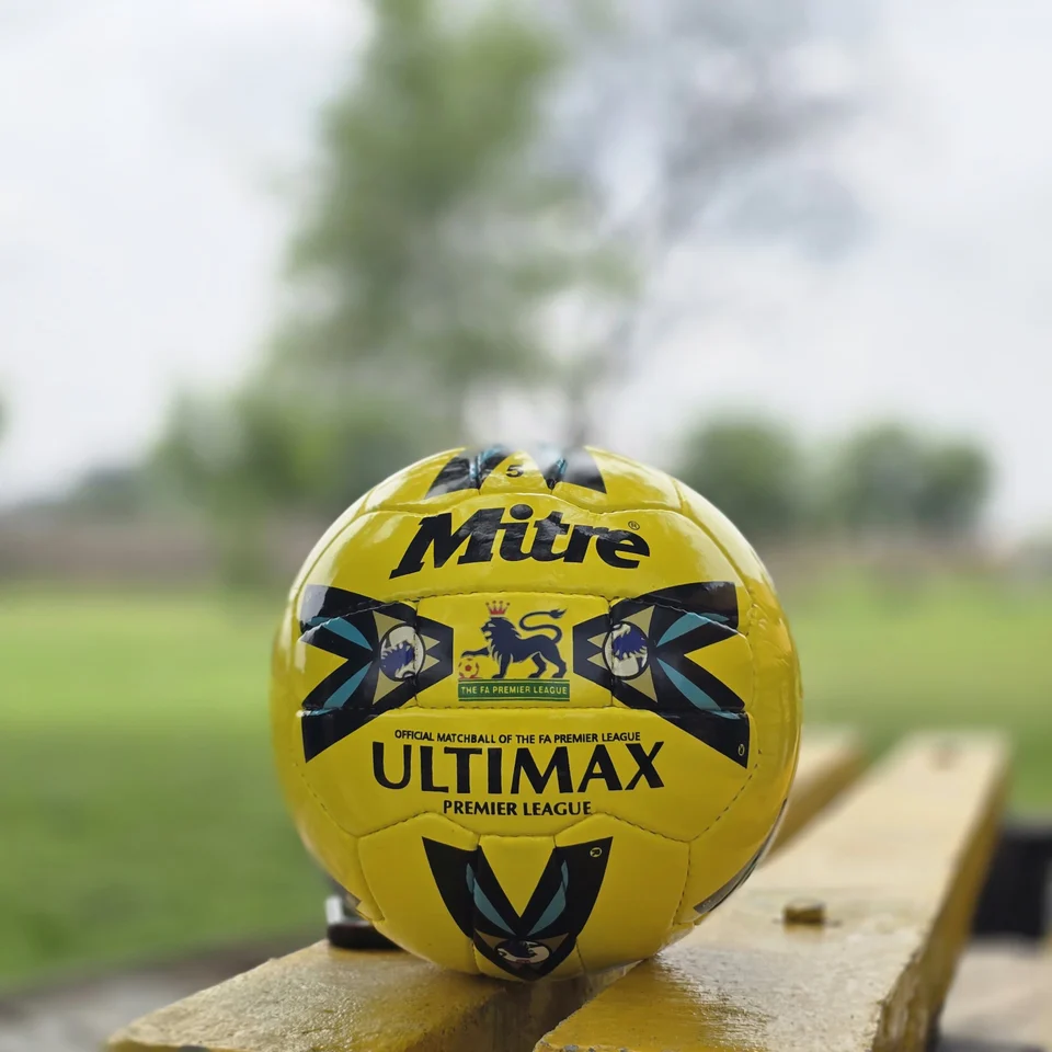 Yellow Ultimax-Style Printed Hand-Stitched Football front view - yellow handmade football with black angular graphics and visible Ultimax-style printed text
