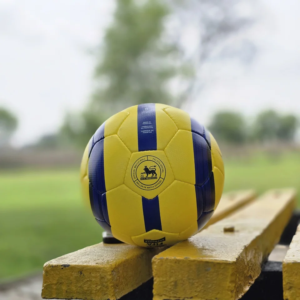 Yellow Ultimax-Style Printed Hand-Stitched Football side view - yellow handmade football with black angular graphics and visible Ultimax-style printed text