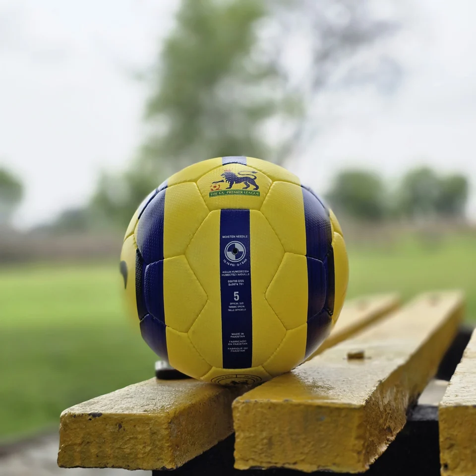 Yellow Ultimax-Style Printed Hand-Stitched Football side view - yellow handmade football with black angular graphics and visible Ultimax-style printed text